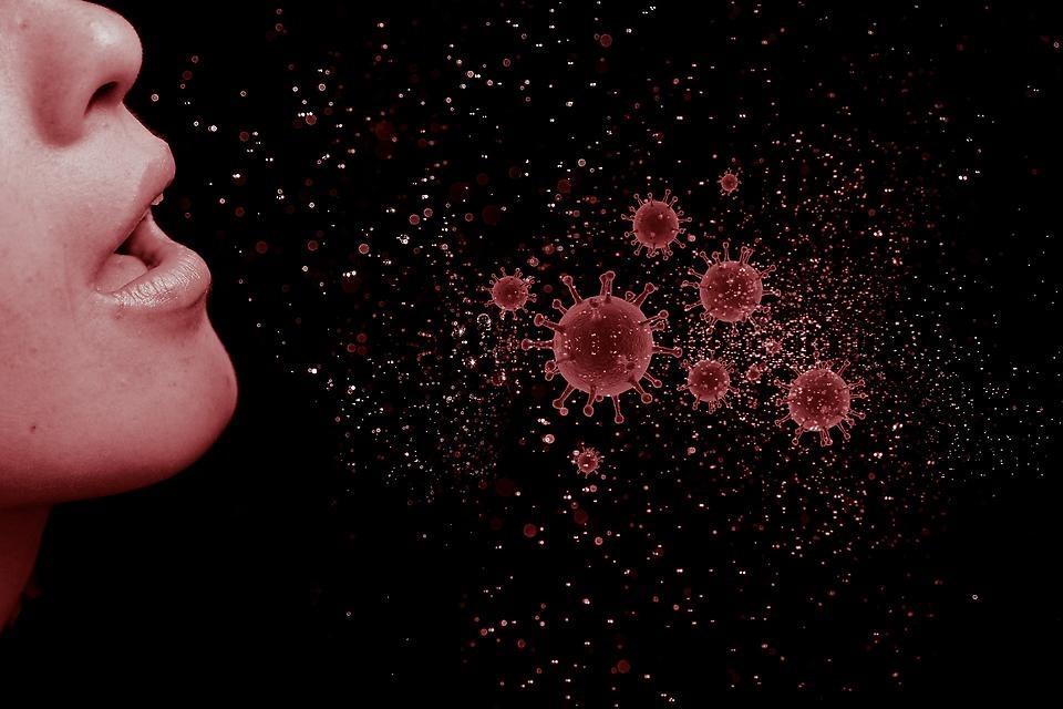Viruspartiklar som flyger ut ur en mun.