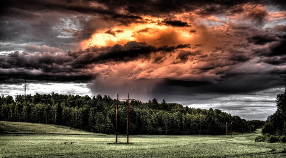 En dramatisk himmel ovanför ett fält och en elledning.