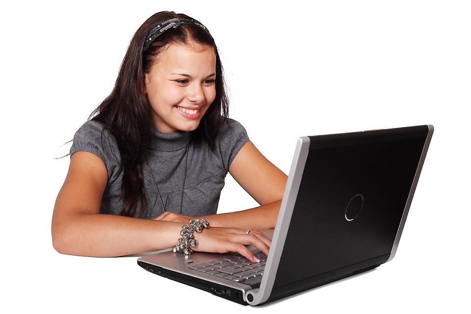 Tonårsflicka som sitter framför en bärbar dator.